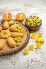 hal right side of cookies on wooden plate and a bowl of yellow flowers and palms of marble ground