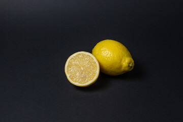 Lemons on a black background. Citrus fruit. Healthy food. Sliced lemon. Sour fruit