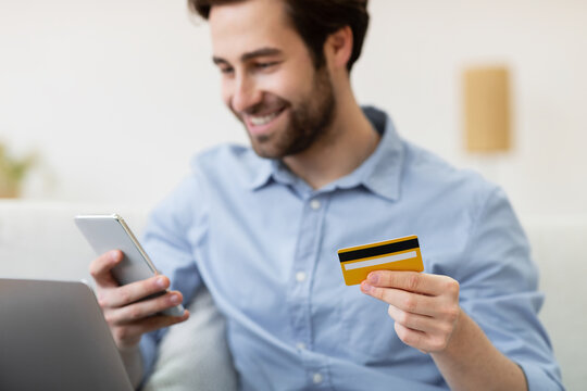 Joyful Guy Shopping With Cellphone And Credit Card At Home