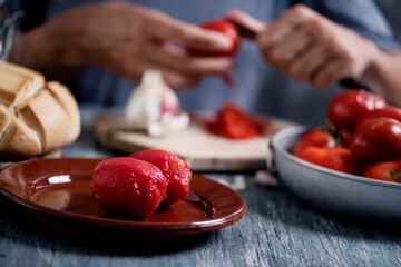 man peeling scalded tomatoes