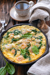 Shrimp omelet with fresh spinach. A large portion is cooked in a cast iron skillet.