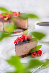 Chocolate cheesecake with fresh raspberries and mint leaves.
