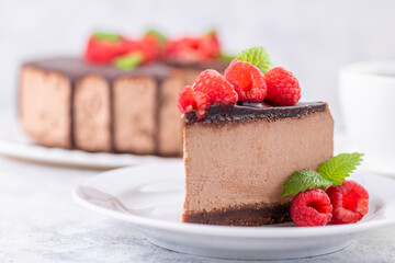 Chocolate cheesecake with fresh raspberries and mint leaves.