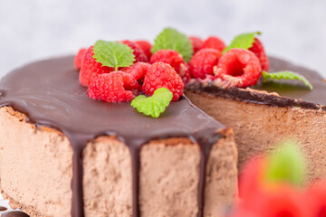 Chocolate cheesecake with fresh raspberries and mint leaves.