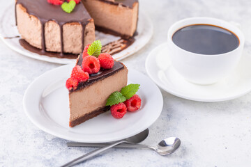 Chocolate cheesecake with fresh raspberries and mint leaves.