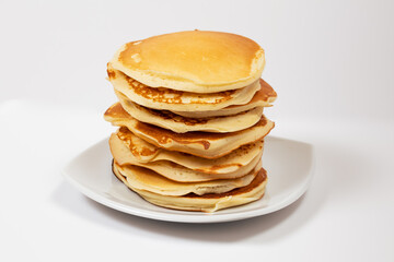 Stack of pancakes without any trimmings on a white plate in a white background.