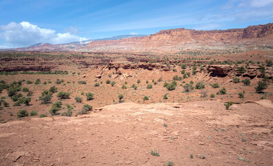 Amazing sandstone monoliths in a barren desert prairie on a blue partly cloudy summer day at Capitol Reef National Park in Torrey Utah