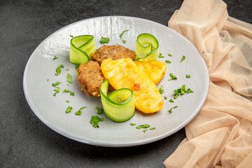 Delicious homemade cutlet meal along with potatoes next to towel on dark table