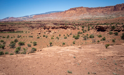 Fototapeta premium Amazing sandstone monoliths in a barren desert prairie on a blue partly cloudy summer day at Capitol Reef National Park in Torrey Utah