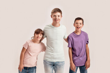 Three cheerful teenaged disabled children with Down syndrome and cerebral palsy smiling at camera...
