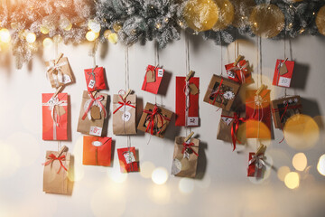 Christmas Advent calendar with gifts and decor hanging on light wall. Bokeh effect