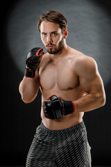 A man in Boxing gloves. A man Boxing on a black background. The concept of a healthy lifestyle