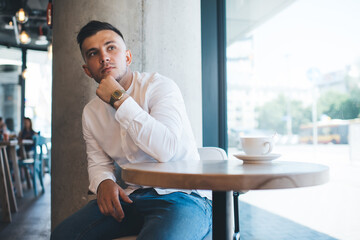 Pensive man looking away with interest while sitting in cafe