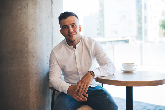 Cheerful man looking at camera while sitting at table
