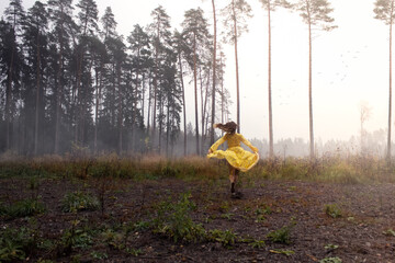 A girl in a gloomy misty forest in a bright yellow dress. the girl got lost in the thicket.