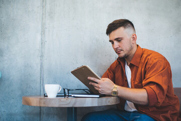 Serious man reading notes on clipboard in cafe