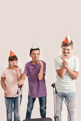 Three disabled children with Down syndrome and cerebral palsy wearing birthday caps and blowing...