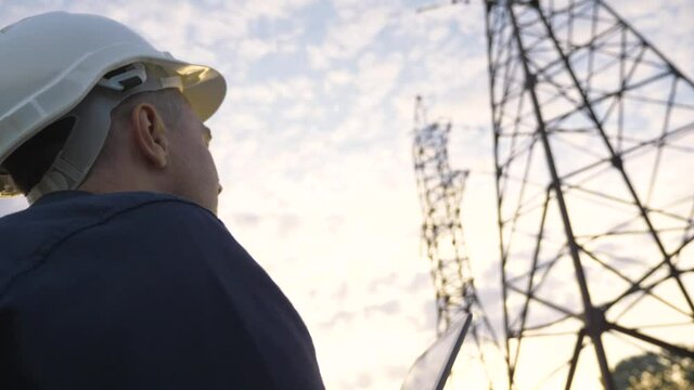 Power Engineer uses software technology to run a bastard project in the power industry. Working engineer with software application tablet. Telecommunications industry