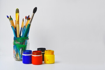paint brushes in a glass jar. Painting brushes and gouache on white background