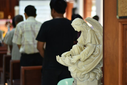 Angel statue in church isolated with people blurred background.
