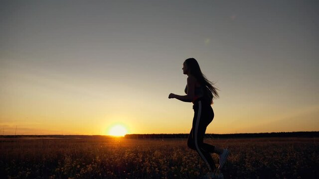 The girl runs in the park on the grass. Girl runner at sunset. Fitness girls training. Grass runners training. active lifestyle, cardio jogging outdoors. Sporty girl jogging on the grass in the park