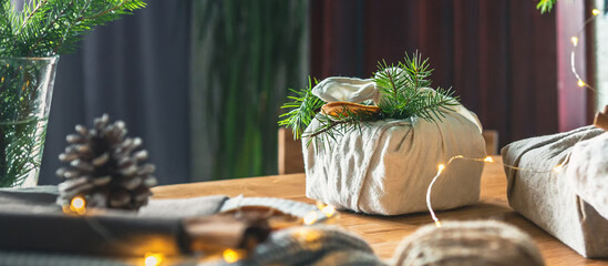 Christmas gifts. New year and gift wrapping, zero waste furoshiki, eco friendly gift wrapping in kraft paper on eco christmas background, eco christmas holiday concept, banner with eco decor