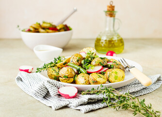 Tasty hot potato salad with green beans, fresh radishes and herbs dressing with olive oil and mustard sauce, light background.