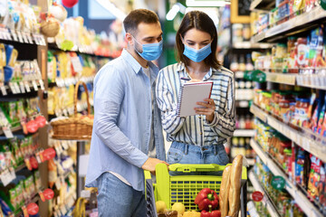 Couple Wearing Face Masks In Supermarket, Checking Shopping List