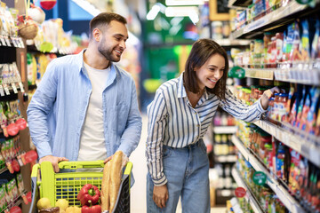 Young couple with the cart shopping in supermarket