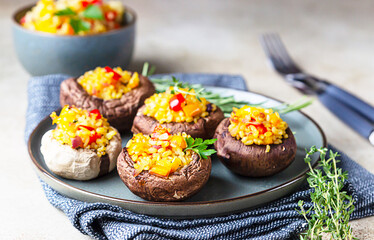 Stuffed portobello mushrooms with bulgur, vegetables and aromatic herbs on concrete background. Vegetarian food.