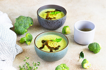 Broccoli or spinach green soup with aromatic spicy oil in bowl. Vegan healthy food. Stone background.