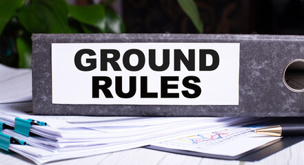 GROUND RULES is written on a gray file folder next to documents. Business concept