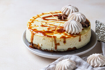 Vanilla cheesecake with carrot cake crust served with salty caramel topping and meringue, light concrete background.