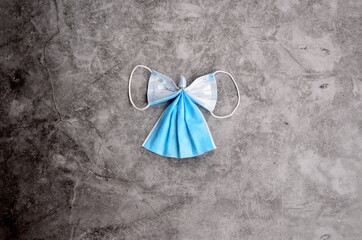 Angel from blue face protection mask on a gray concrete background.COVID-19. Christmas concept on...