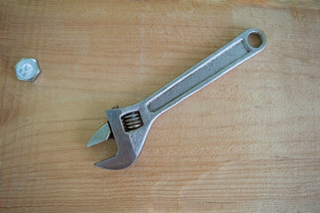 Old adjustable wrench made of metal on a wooden board. Universal adjustable tool. Household work,...