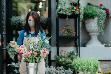 Woman florist at her own floral shop taking care of flowers