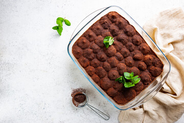 Traditional Italian dessert tiramisu in a glass backing form on light background, top view