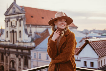 Fashionable happy smiling woman wearing trendy beige hat, rhinestones earrings, brown faux fur...