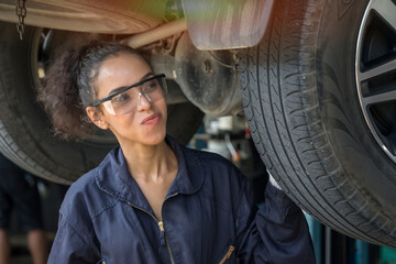 Fototapeta na wymiar young engineer mechanic, a car repair technician, wears a uniform, checks the engine, fixes cars and changes wheels in the garage
