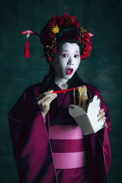 Tasty noodles. Young japanese woman as geisha isolated on dark green background. Retro style, comparison of eras concept. Beautiful female model like bright historical character, old-fashioned.