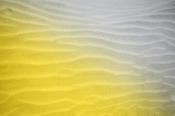 The texture sandy surface with a wavy surface formed by wind sand in trendy colors 2021 year - yellow and gray.