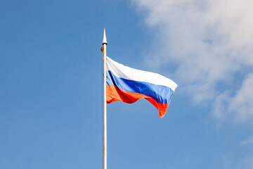 Fototapeta na wymiar The flag of the Russian Federation flutters in the wind against the blue sky