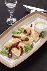 traditional ukrainian food dumplings varenik with mushroom and sour cream and vodka shot on the table