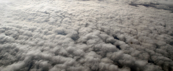 Aerial view of clouds and sky. Bird eye view from airplane window. Clouds panorama from airplane