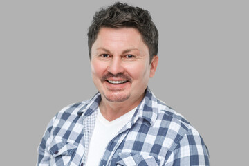 Portrait of happy successful handsome middle aged business man in casual checkered shirt, mustache standing and looking at camera with toothy smile. indoor studio shot, isolated on gray background.