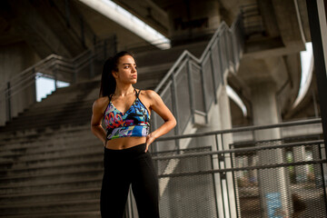 Young fitness woman taking a break from running in urban environment