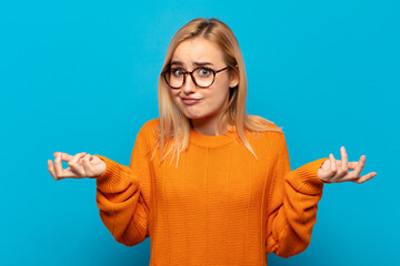 young blonde woman feeling puzzled and confused, doubting, weighting or choosing different options...