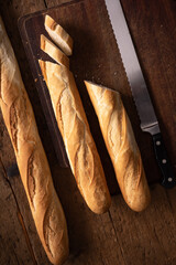 baguette on wooden table with knife. baguette cut in half. slices of bread. typical French bread