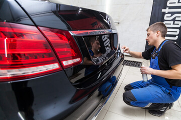 The process of applying a nano-ceramic coating Ceramic Pro 9h and Light on the car's hood by a male...