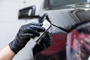 The process of applying a nano-ceramic coating on the car's fender by a male worker with a sponge...